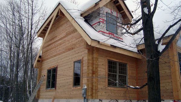 The outside of the flat-flat milled logs. Siding on gable windows still under construction.